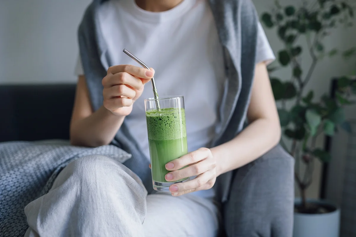 Foto colorida de mulher segurando copo com suco verde - Nutricionistas explicam os benefícios do suco verde detox para o corpo - Metrópoles