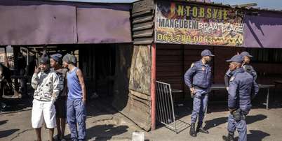 Policiais sul-africanos cercam um estabelecimento onde dez pessoas morreram em um tiroteio na madrugada deste domingo (27), no munic&iacute;pio de Lwandle, nos arredores da Cidade do Cabo. Foto: AFP - GIANLUIGI GUERCIA / RFI