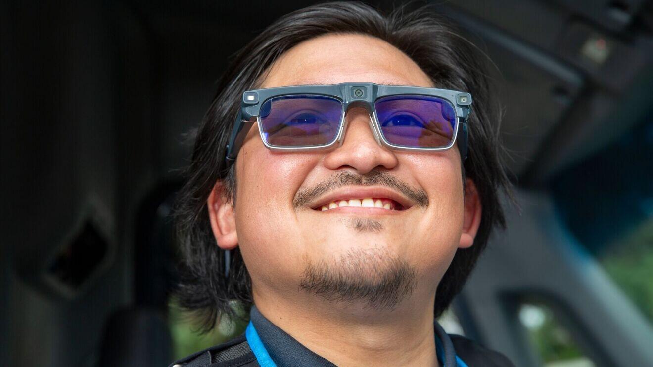 A man wears AI glasses and smiles.