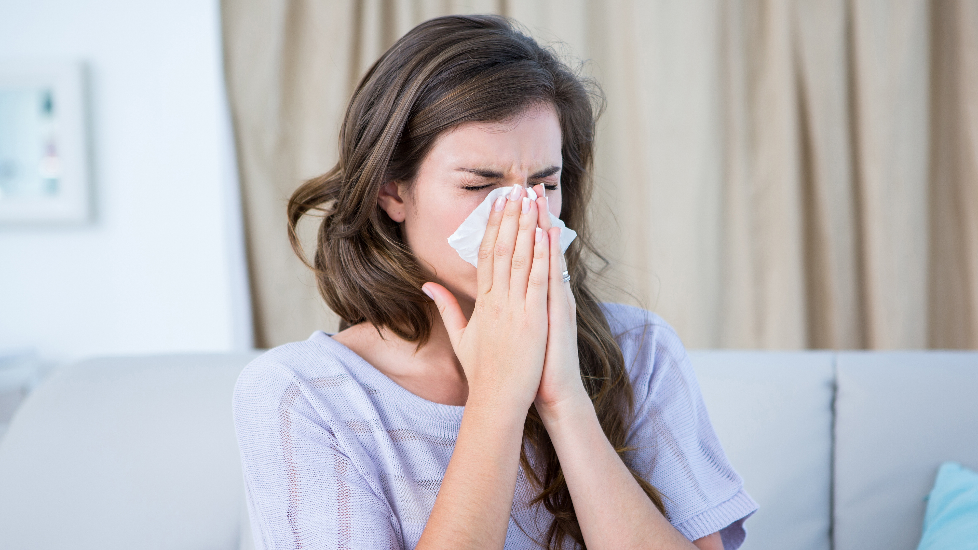 woman sitting on a couch blowing her nose