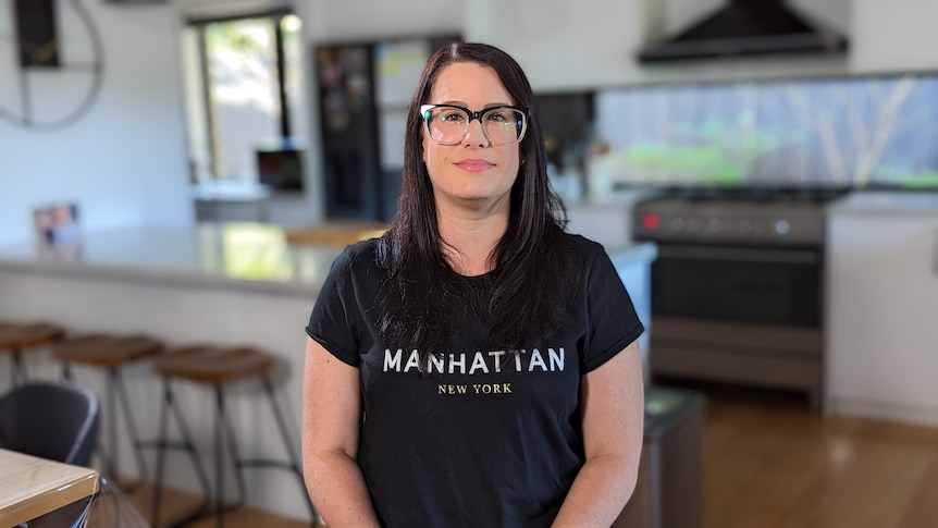 A young white woman with long dark hair standing in a kitchen