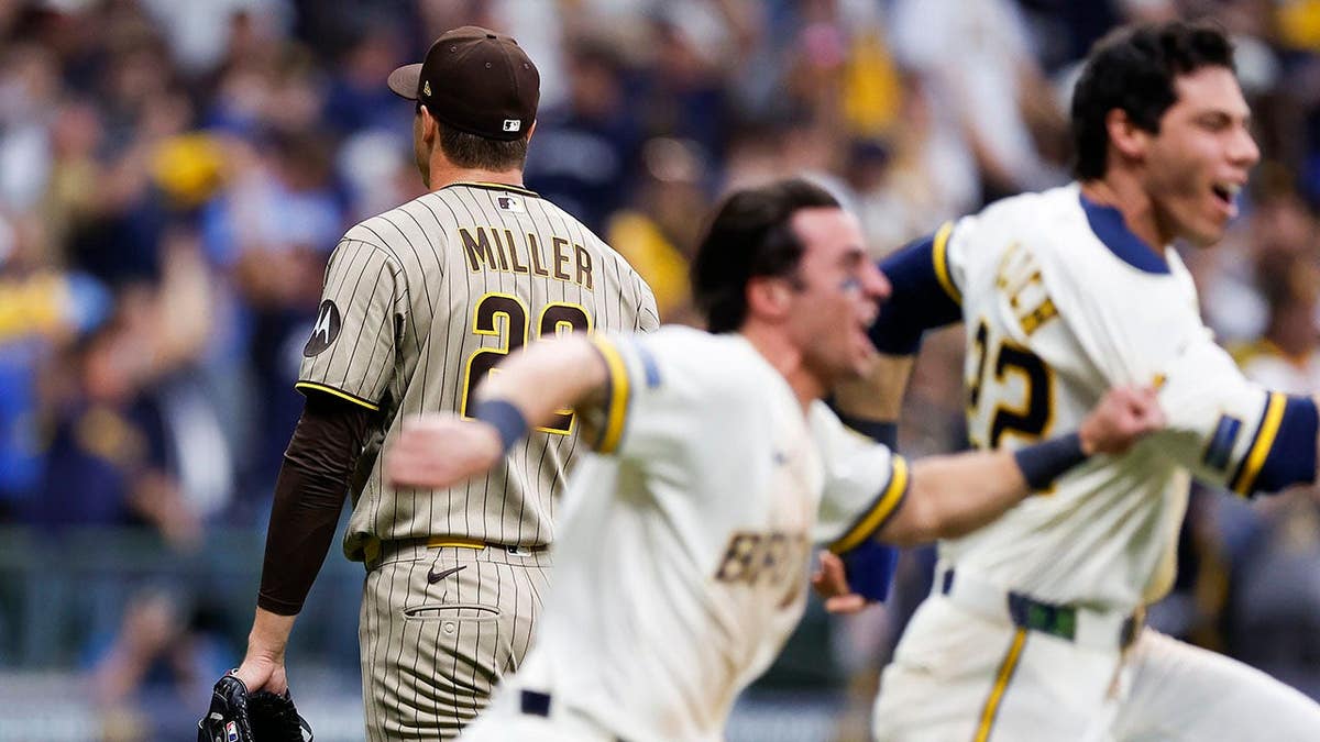 Mason Miller #22 walks off the field as Milwaukee Brewers players celebrate at American Family Field.