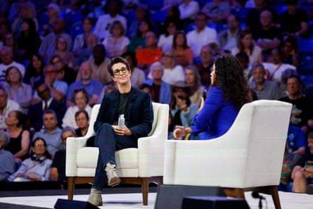 Two women sitting on chairs placed on a stage.