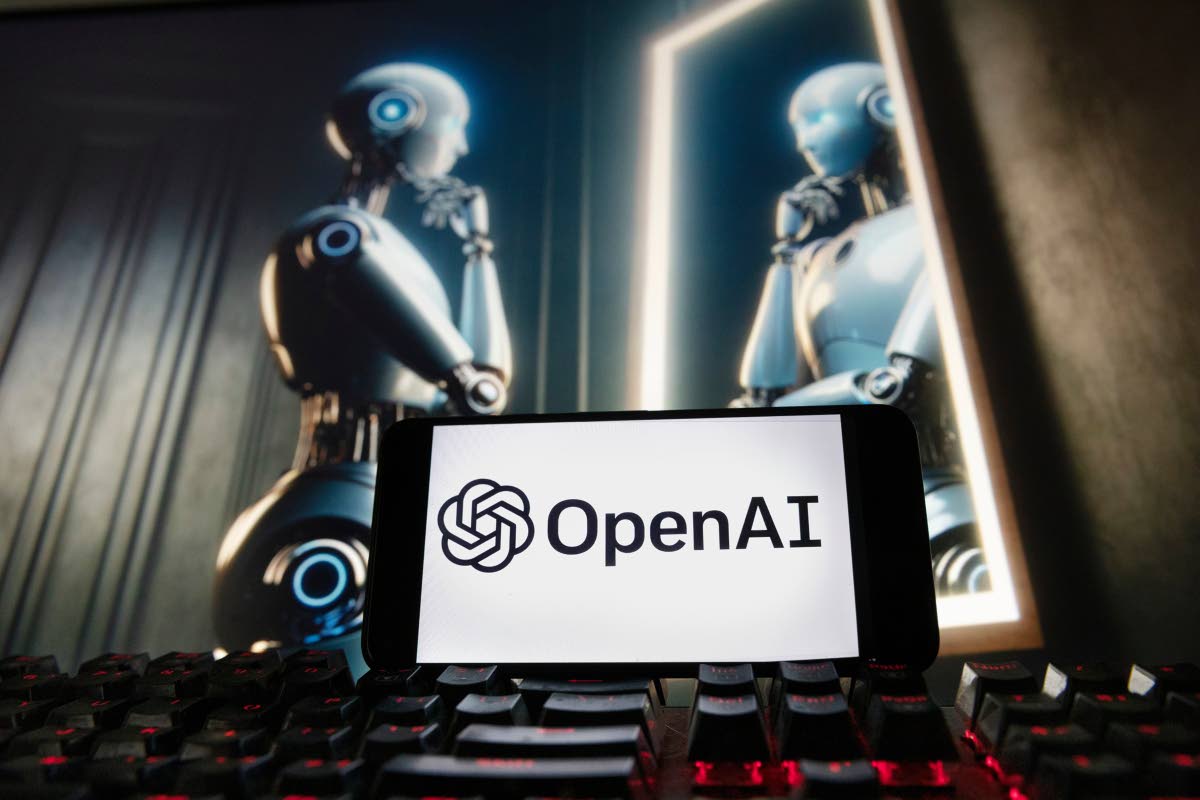 FILE - The OpenAI logo is displayed on a cellphone with an image on a computer monitor generated by ChatGPT’s Dall-E text-to-image model, December 8, 2023, in Boston. (AP Photo/Michael Dwyer, File)