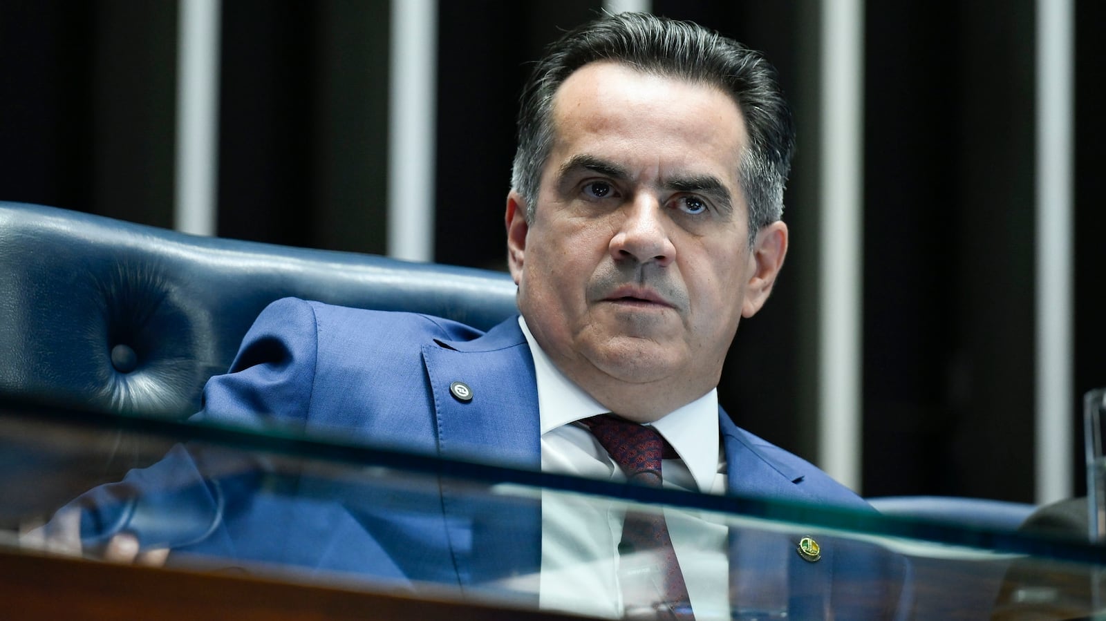 Homem de terno, no Senado, observa com olhar desconfiado